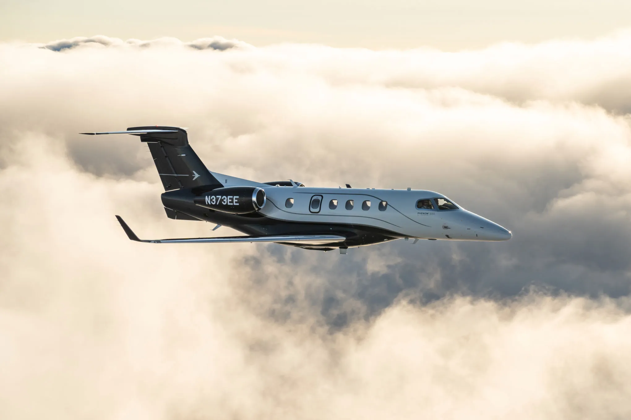 Embraer Phenom 300E in flight above a sea of cloud