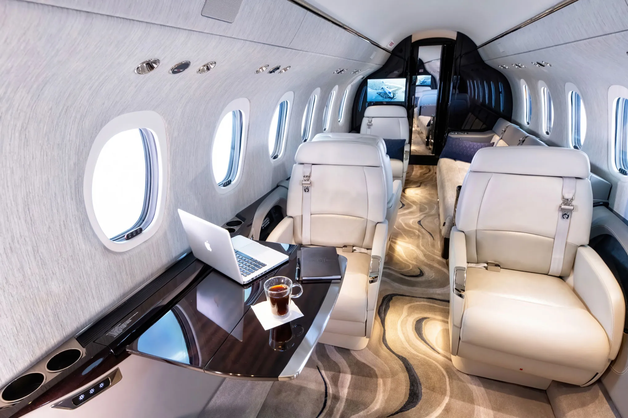 Cessna Citation Longitude cabin club seats with a laptop and coffee on the table