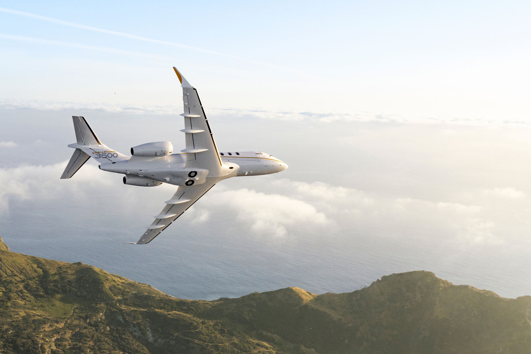 Bombardier Challenger 350/3500 in flight above cloud and coastal hills