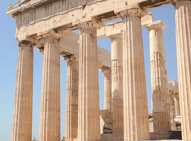 Athens: The weathered marble columns of the Parthenon in close view against a pale sky