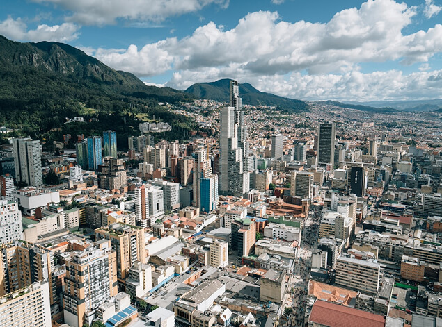 Bogotá: An elevated view across the dense low-rise sprawl of Bogotá to green Andean ridges under cloud