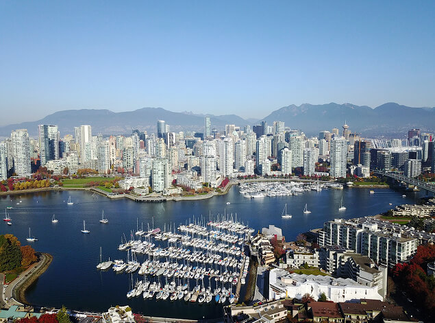 Vancouver: An aerial over False Creek, marina docks packed with yachts below the downtown towers and coastal mountains