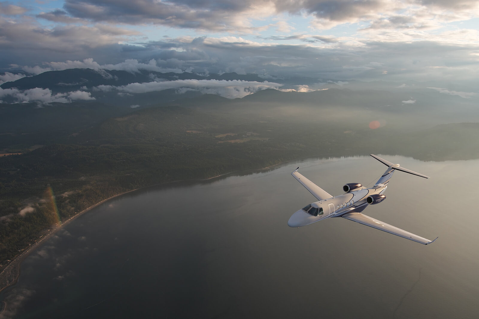 Cessna Citation CJ3 in flight over a lake at golden hour