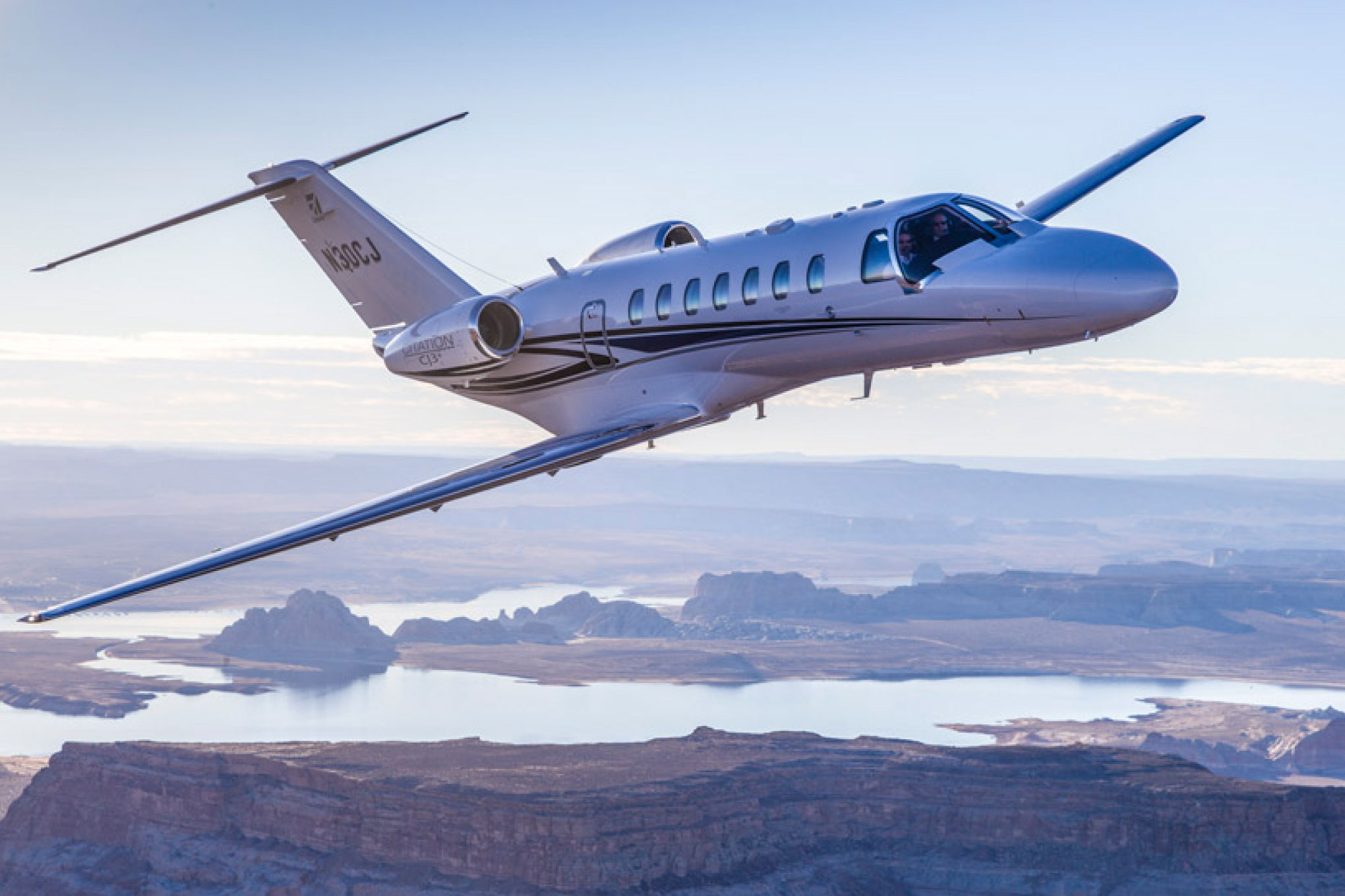 Cessna Citation CJ3 in flight above a desert lake and canyon country