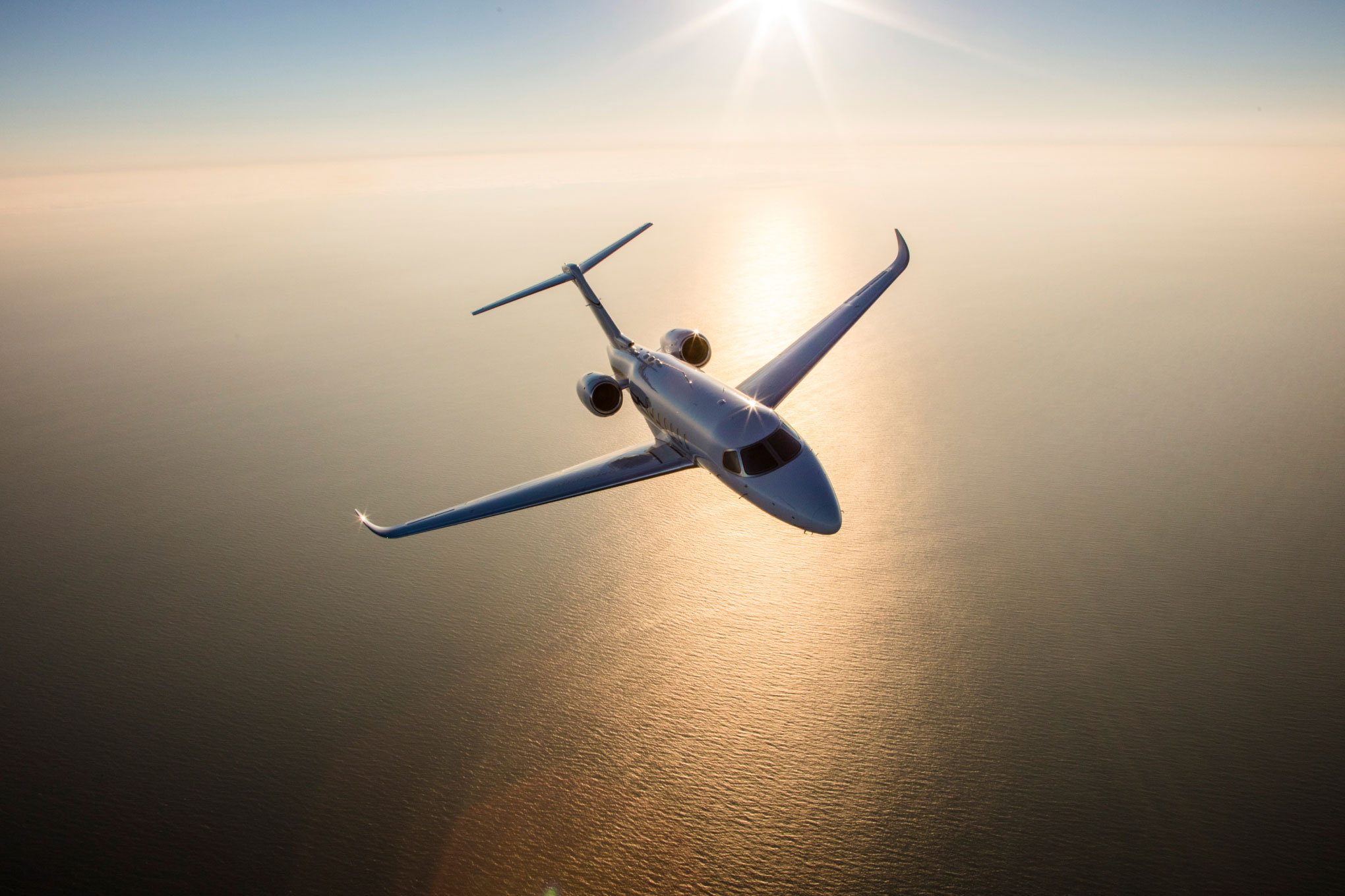 Cessna Citation Longitude in flight over the sea at sunrise