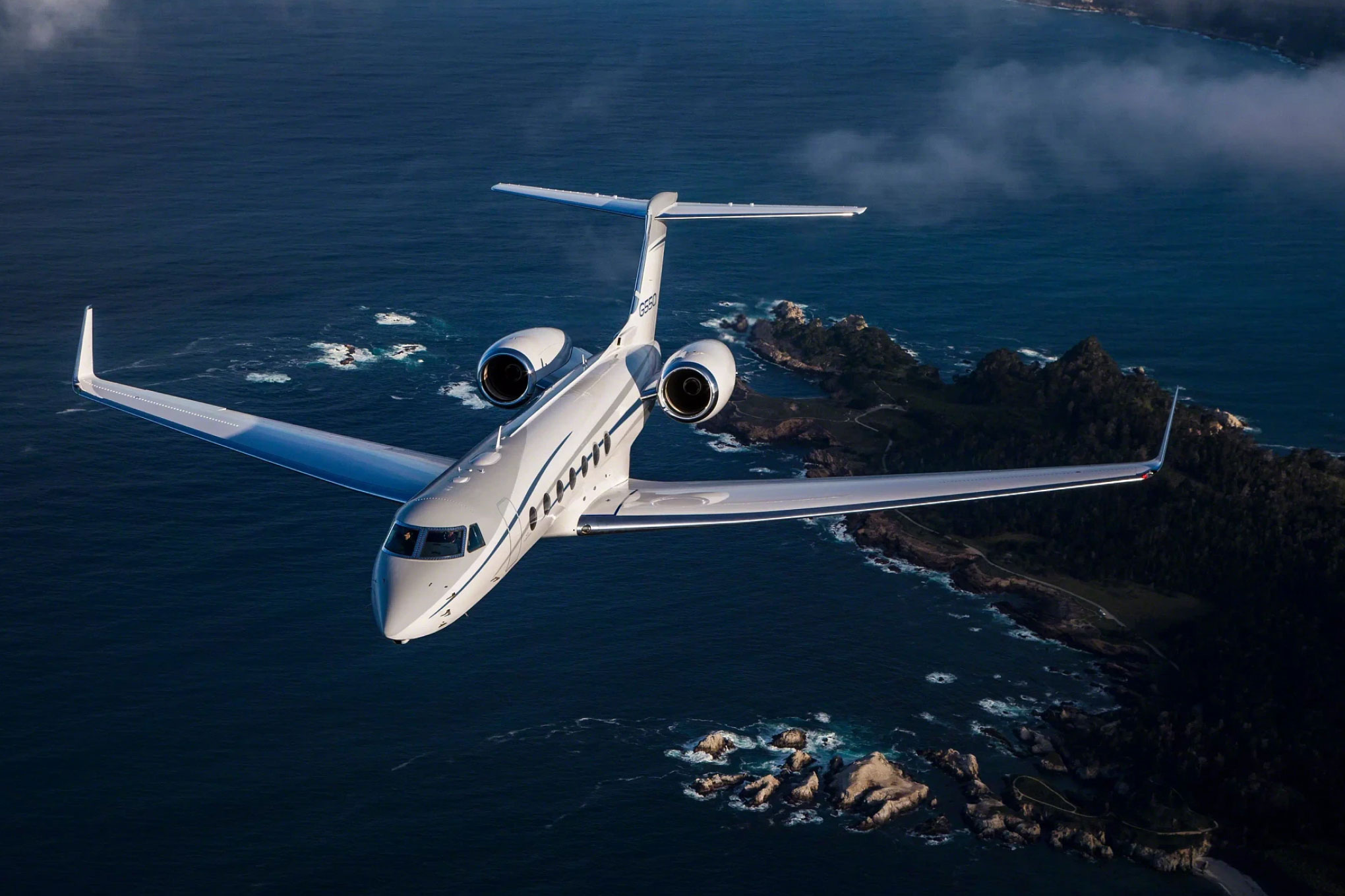 Gulfstream G550 in flight over a rocky coastline