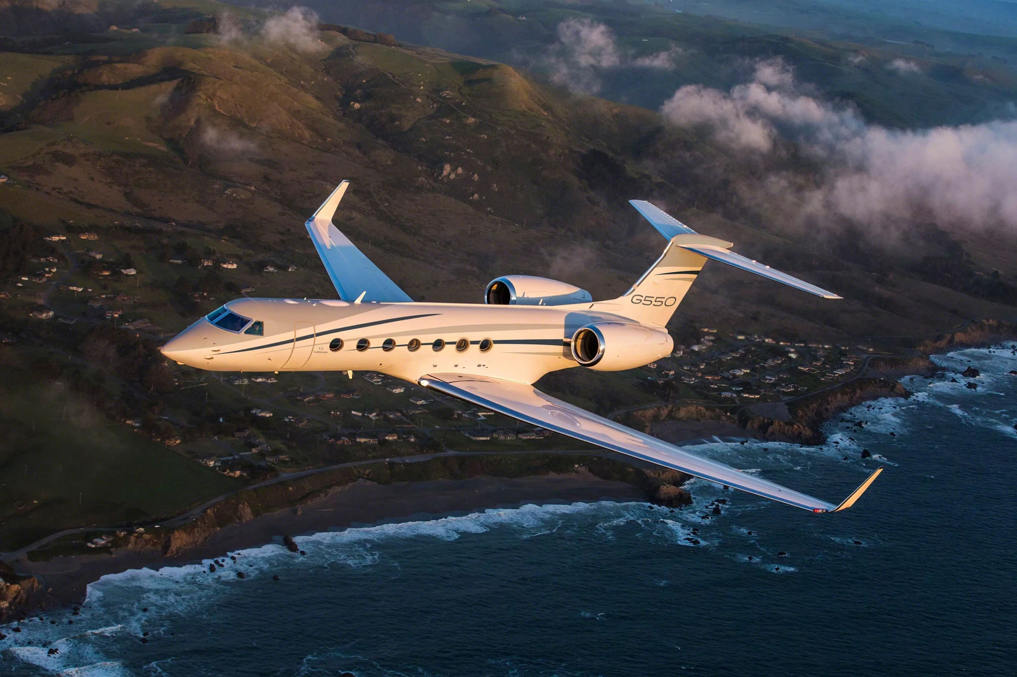 Gulfstream G550 in flight over coastal hills