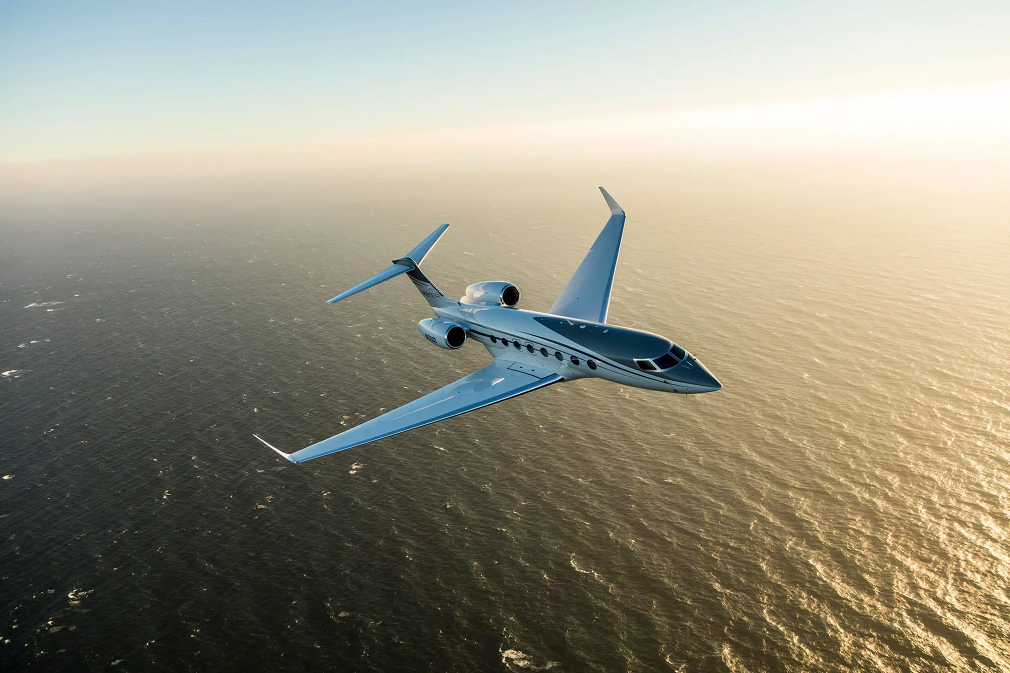 Gulfstream G650 in flight over the ocean at sunset