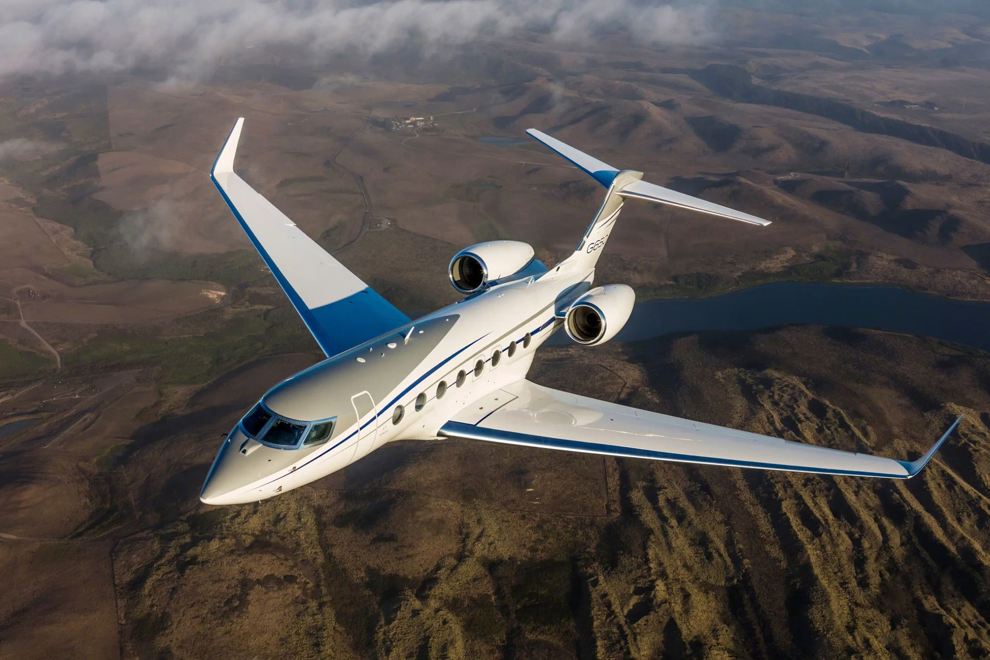 Gulfstream G650 in flight over brown hills