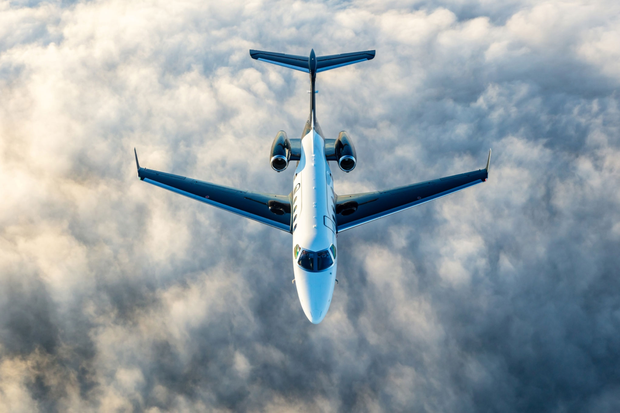 Embraer Phenom 300E seen from above, flying over cloud