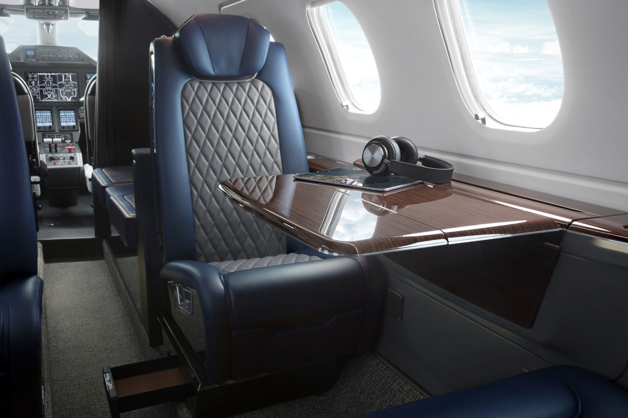 Embraer Phenom 300E cabin seat in quilted navy leather with a burl-wood table