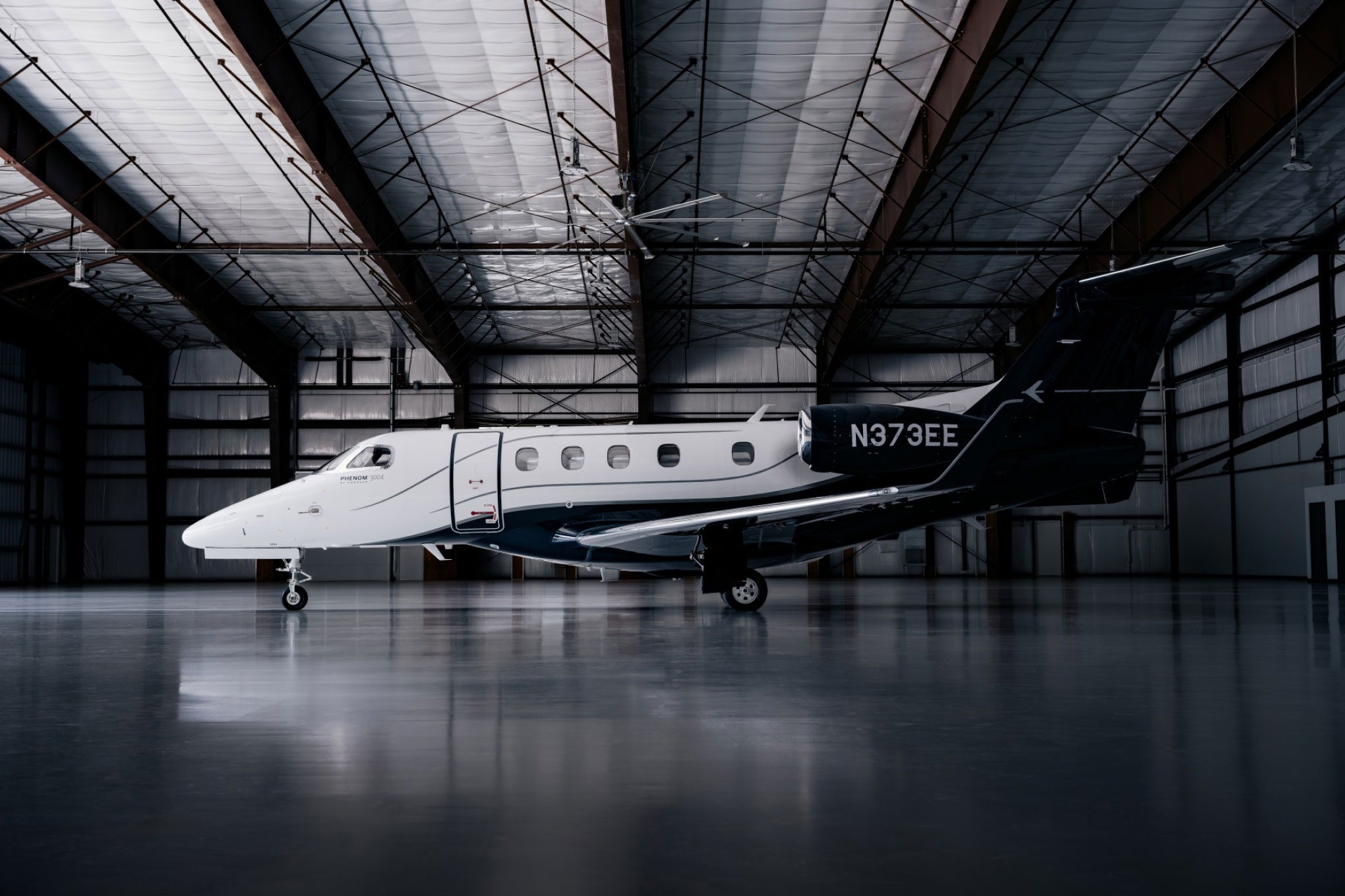 Embraer Phenom 300E parked inside a hangar