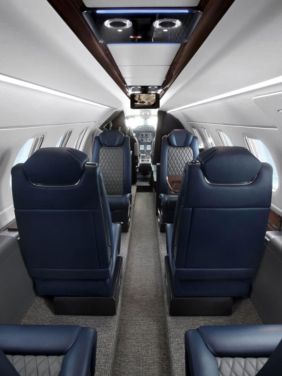 Embraer Phenom 300E cabin aisle between navy leather seats, portrait view