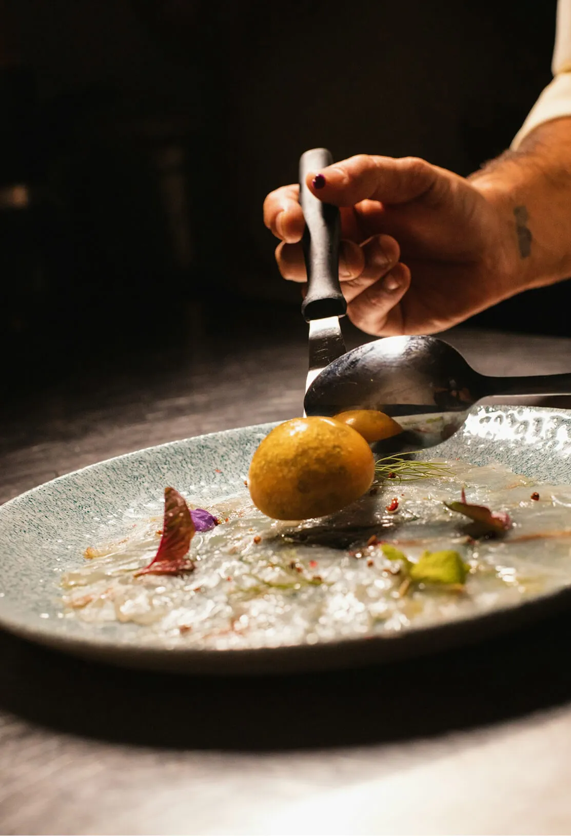 Chef finishing a plated dish with a brush