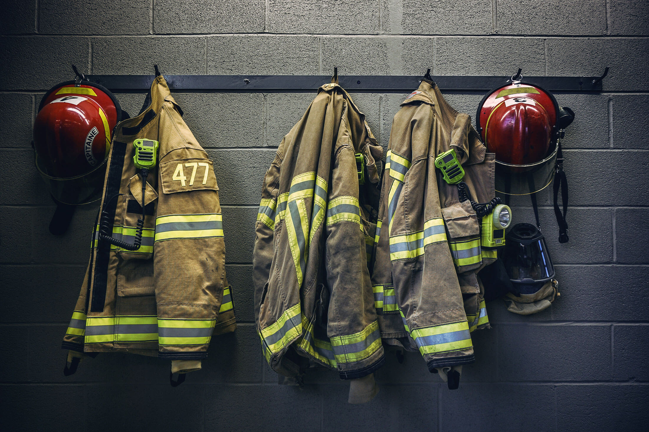 Firefighter turnout gear and helmets hanging on a station wall