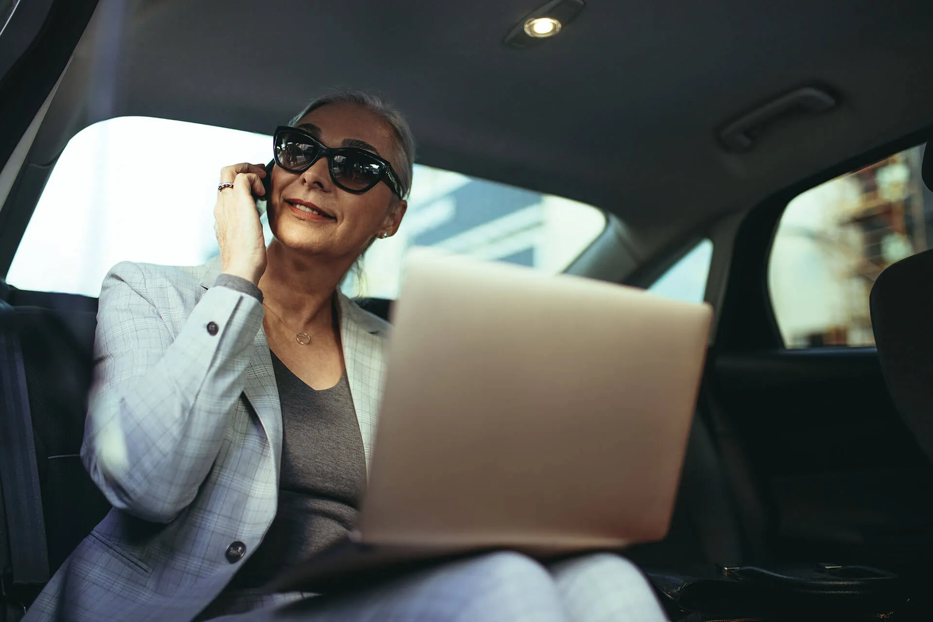 Charter client on a phone call with a laptop in the back of a car
